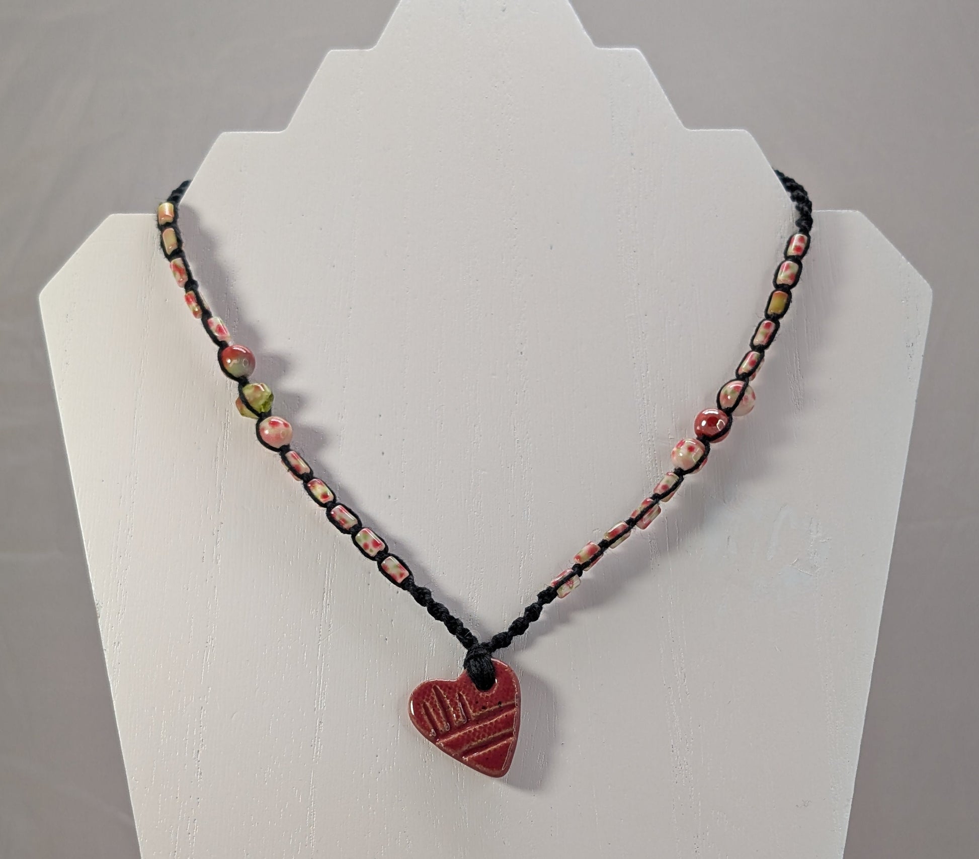 Necklace with a red heart pendant on a white stand