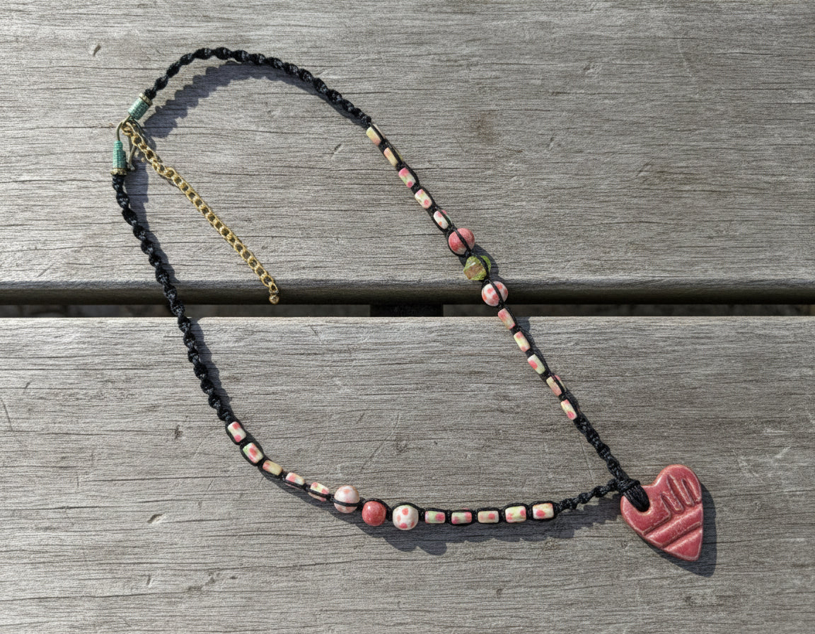 Beaded necklace with a heart-shaped clasp on a light gray background