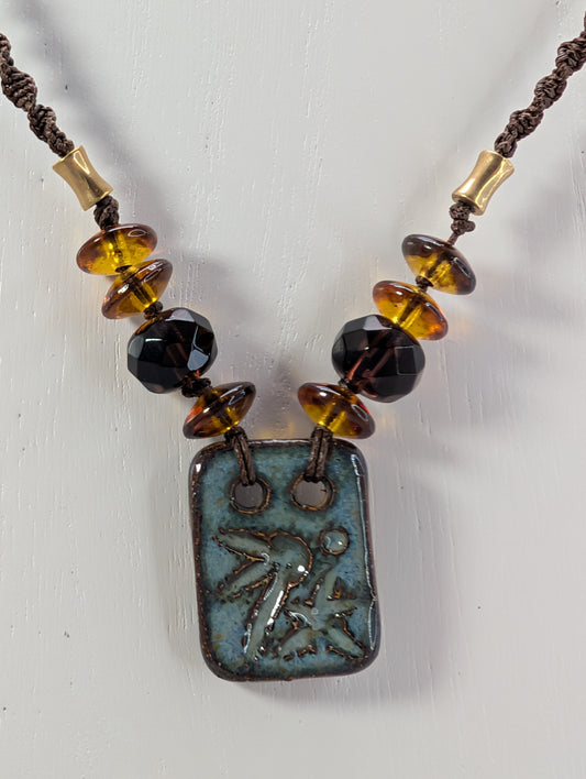 Necklace with beads and a rectangular pendant on a white background