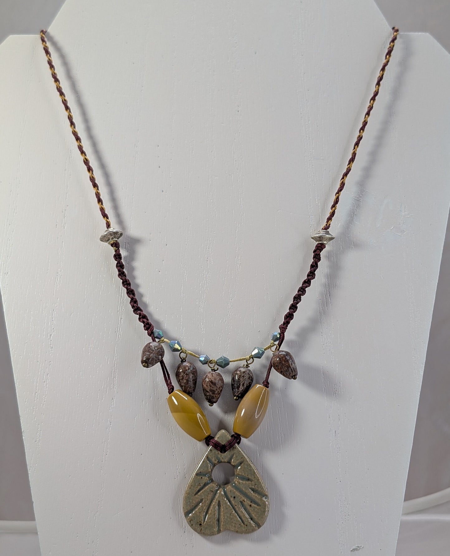 Necklace with natural stone pendant on a white stand