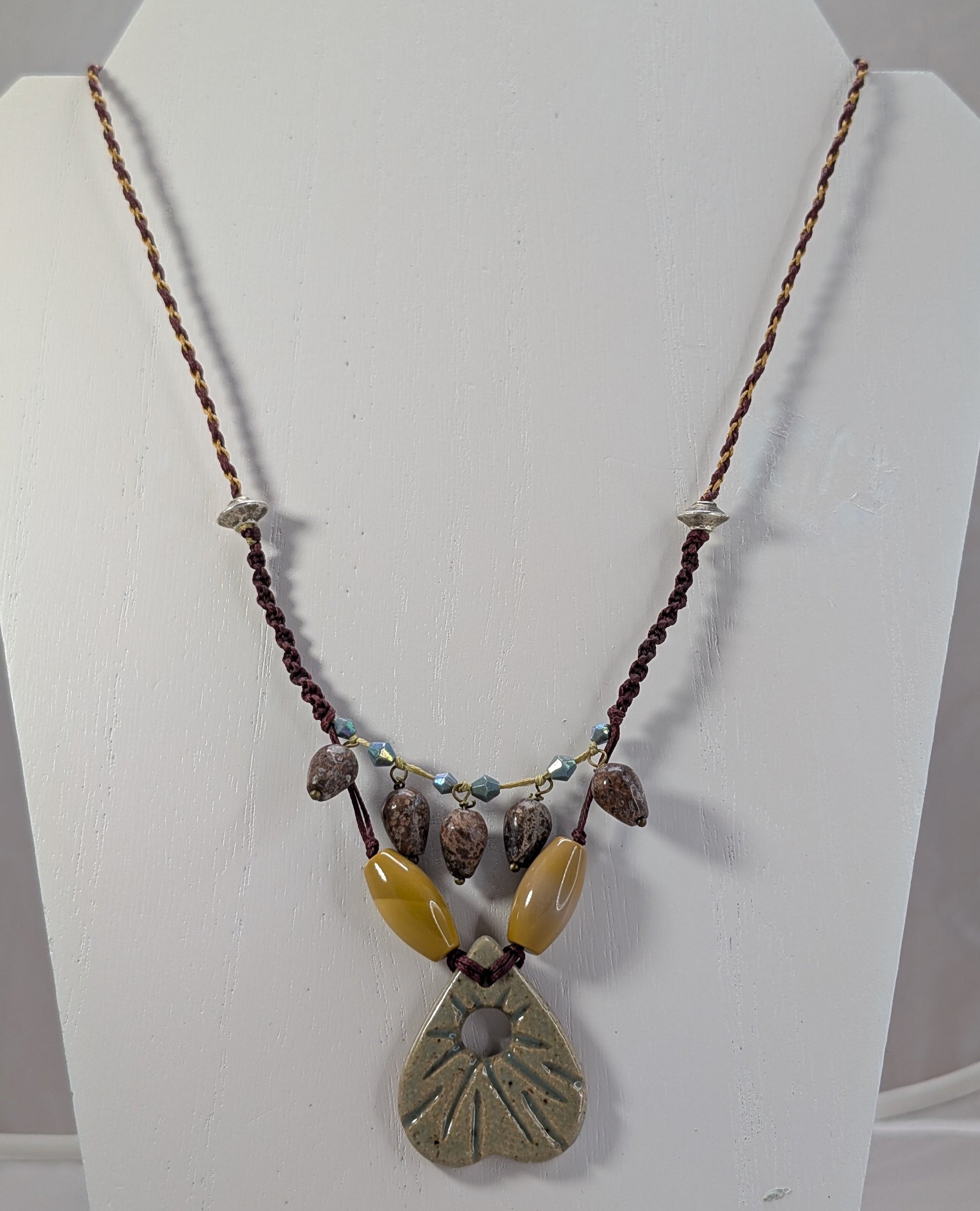 Necklace with natural stone pendant on a white stand