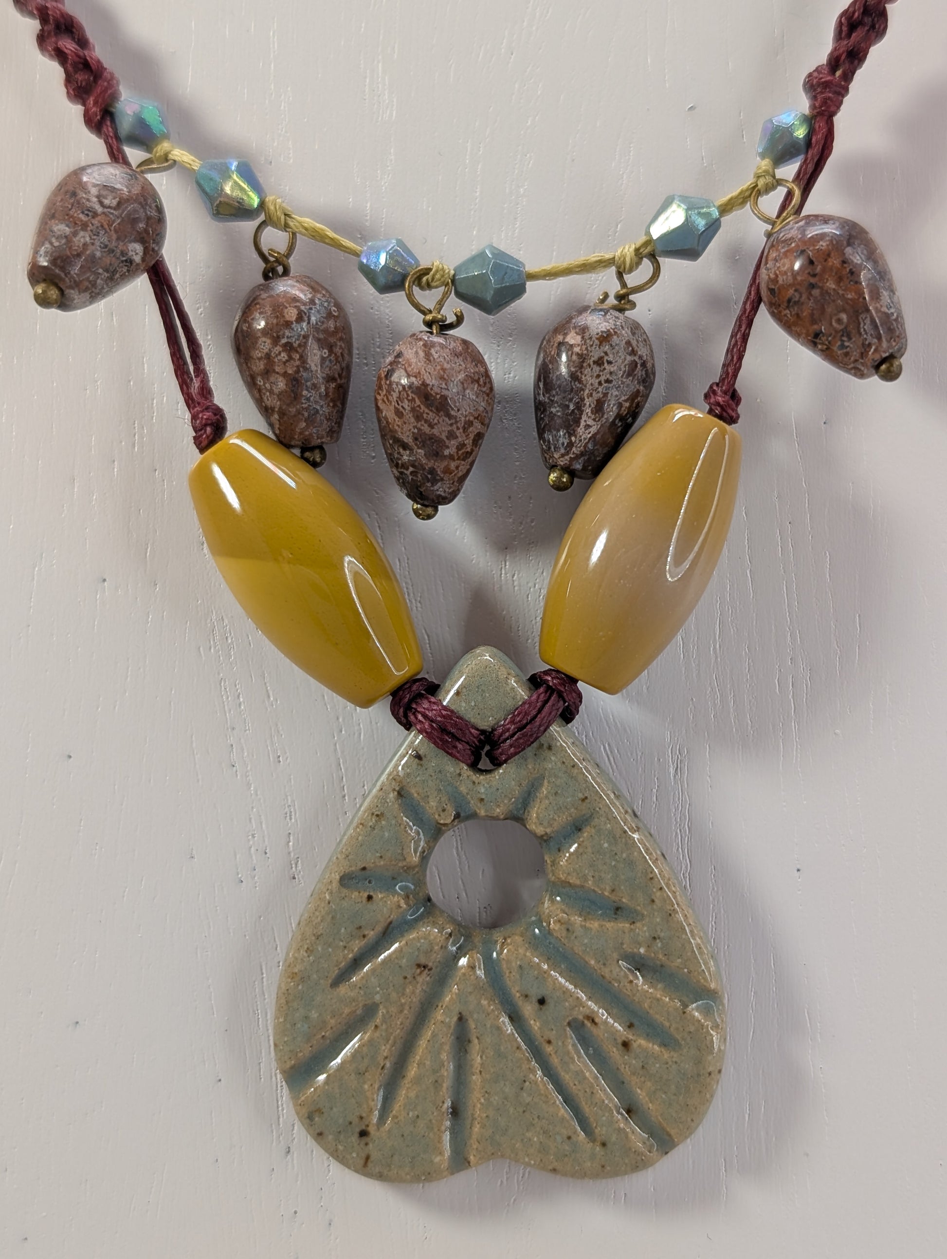 Necklace with a large ceramic pendant and various beads on a white background