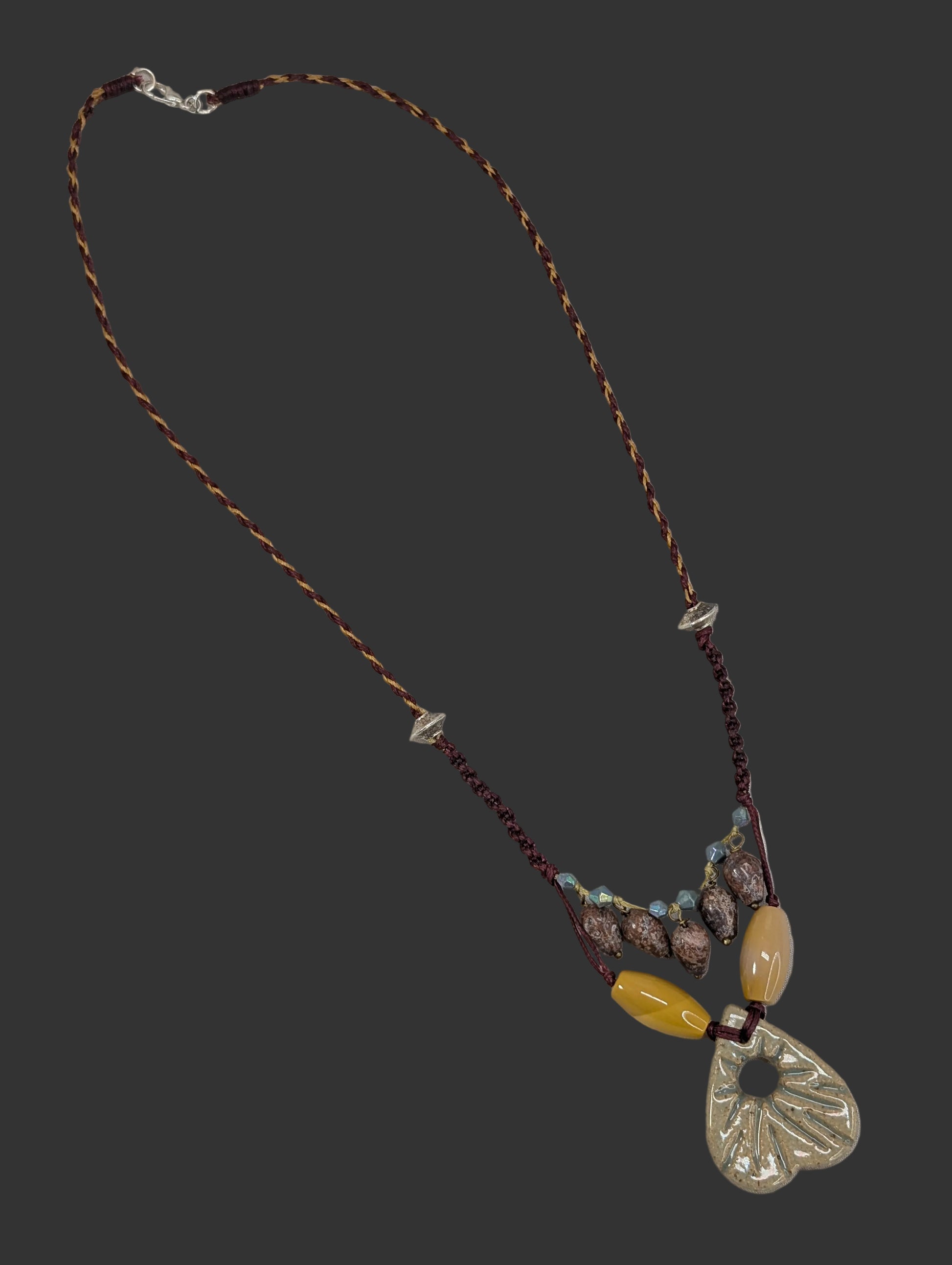 Necklace with beads and a metal pendant on a textured surface