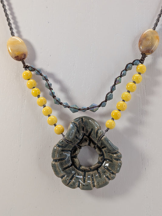 Necklace with yellow beads and a large green stone pendant on a white background