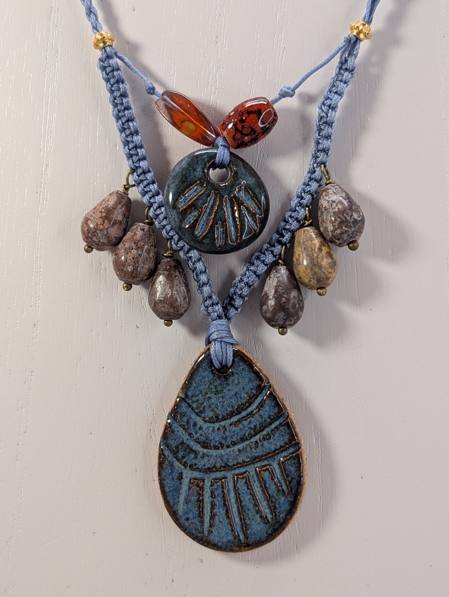 Necklace with blue ceramic pendants and brown beads on a light background