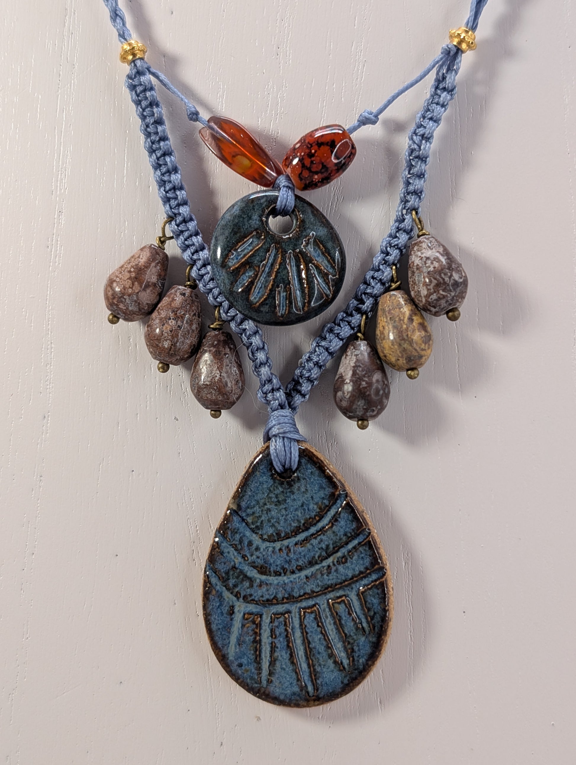 Necklace with blue ceramic pendants and brown beads on a light background
