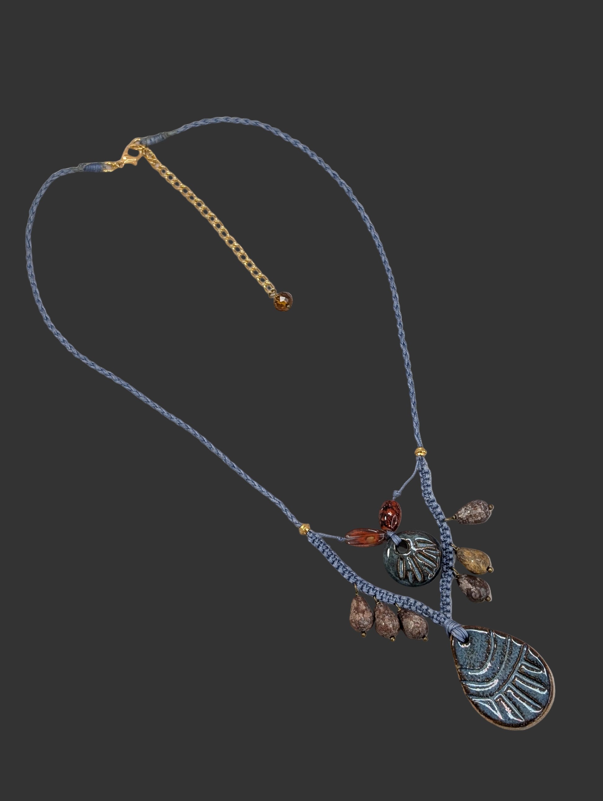 Necklace with beads and leaf-shaped pendants on a wooden surface